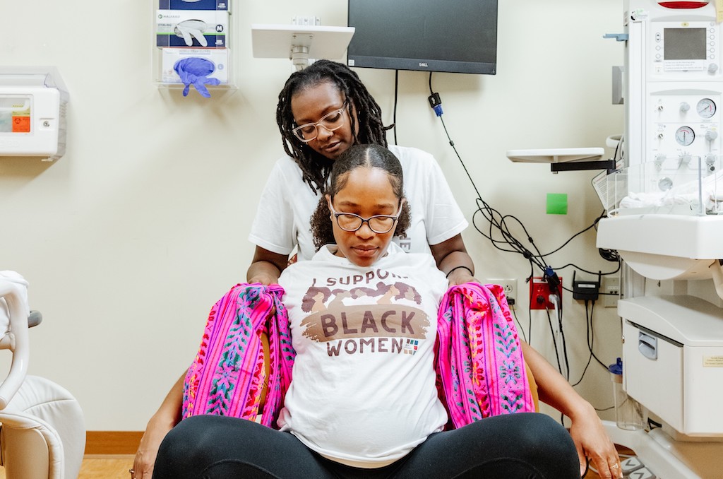 Pregnant woman supported in medical exam room