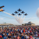 Airshow jets performing over large beach crowd