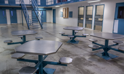 Empty prison common area with metal tables and cells