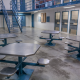 Empty prison common area with metal tables and cells