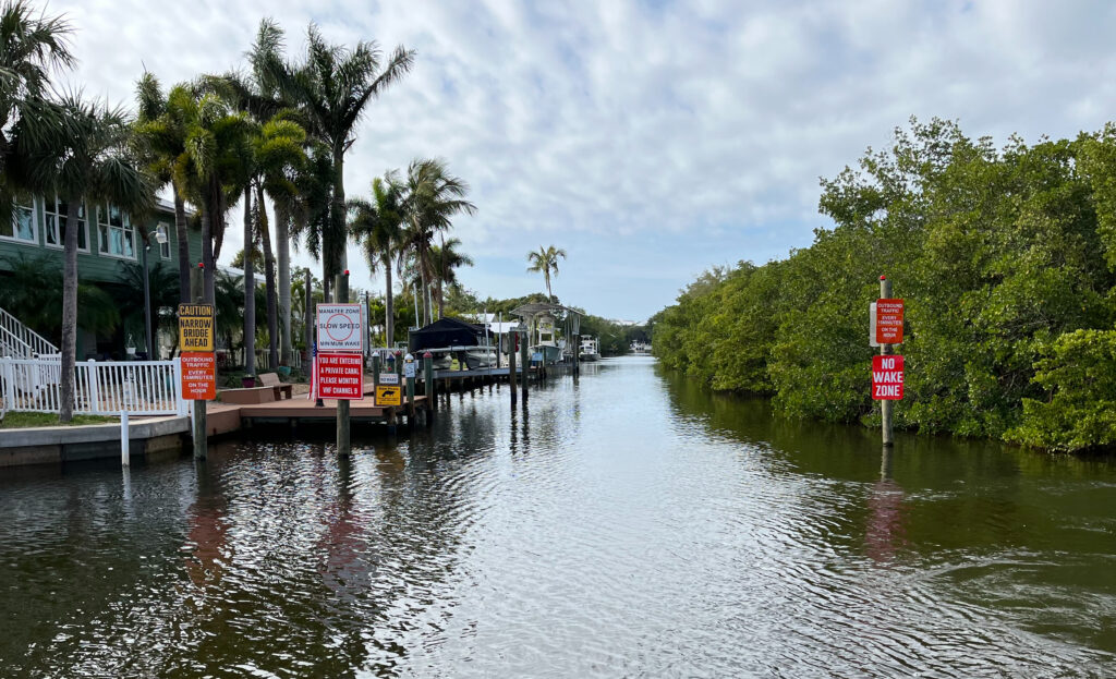 Narrow canal with palm trees and no wake signs
