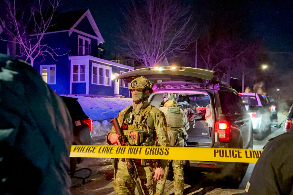 Armed police officers behind yellow crime scene tape