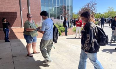 People outside modern building exchanging a flyer