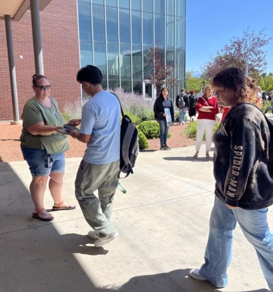 People outside modern building exchanging a flyer