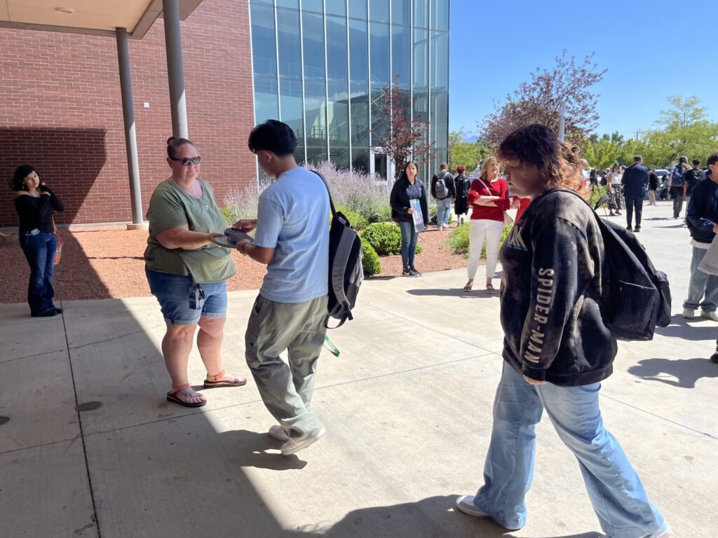 People outside modern building exchanging a flyer