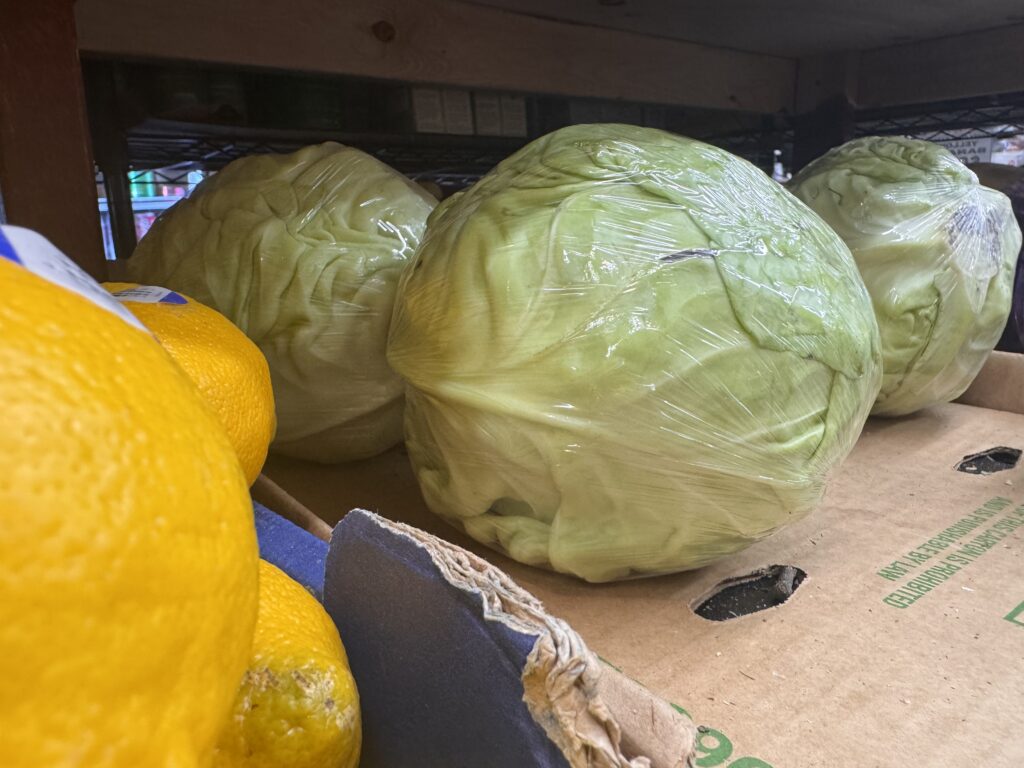 Plastic-wrapped cabbages on grocery store shelf