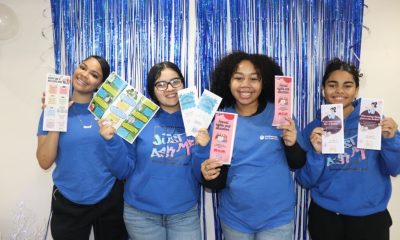 Four women holding educational pamphlets in front of blue backdrop