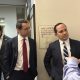 Men in suits discussing in office hallway