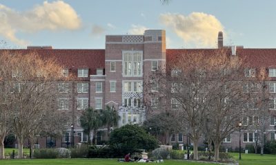 Students relaxing on lawn before brick academic building