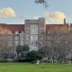 Students relaxing on lawn before brick academic building