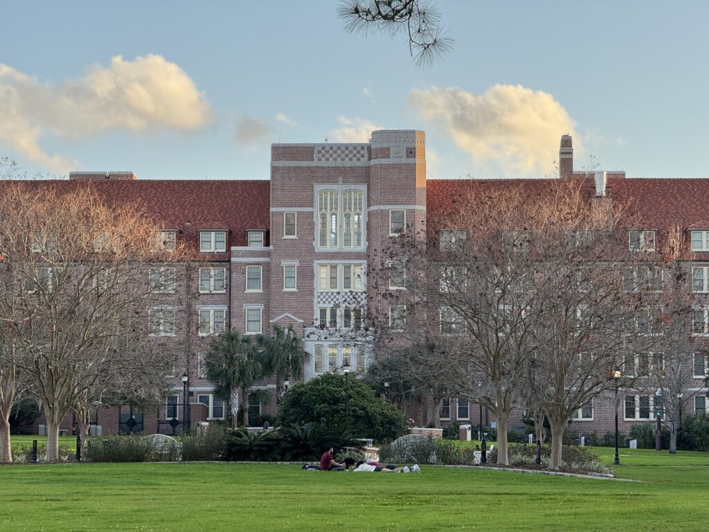 Students relaxing on lawn before brick academic building