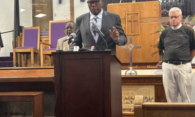 Man speaking at church podium with clergy