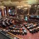 Ornate legislative chamber during session with lawmakers seated