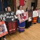 Women holding MMIW protest signs indoors
