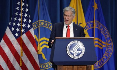 Man speaking at HHS podium with flags
