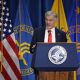 Man speaking at HHS podium with flags