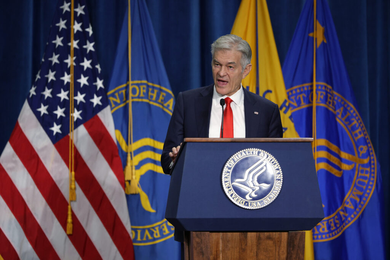 Man speaking at HHS podium with flags