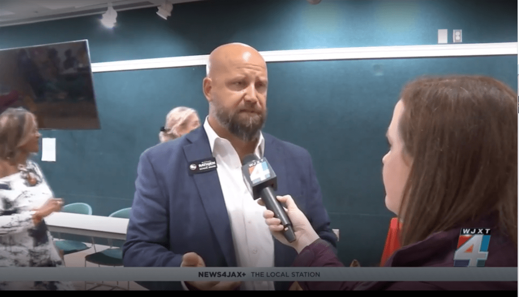 Man being interviewed by reporter indoors