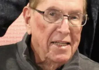 Elderly man wearing glasses and gray sweater