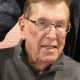 Elderly man wearing glasses and gray sweater