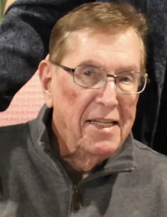 Elderly man wearing glasses and gray sweater