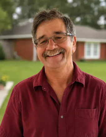 Smiling man with glasses in front of house