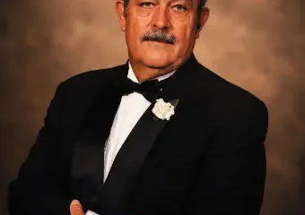 Man in tuxedo posing against brown backdrop