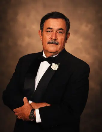 Man in tuxedo posing against brown backdrop