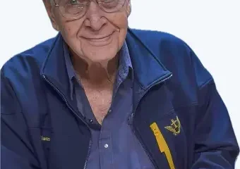 Elderly man with glasses smiling in blue jacket