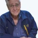 Elderly man with glasses smiling in blue jacket
