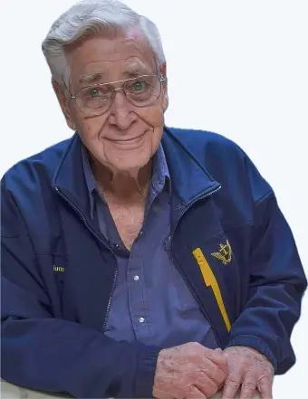 Elderly man with glasses smiling in blue jacket