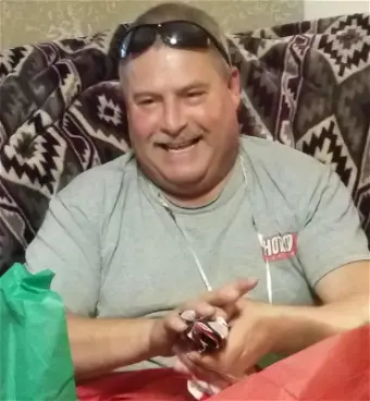 Smiling man holding small gift on couch
