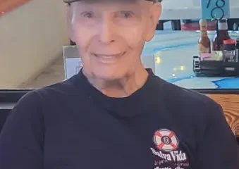 Elderly man wearing black cap seated indoors