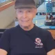 Elderly man wearing black cap seated indoors