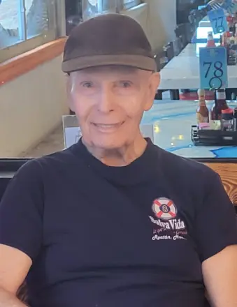 Elderly man wearing black cap seated indoors