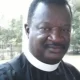 Man wearing clerical collar outdoors smiling at camera