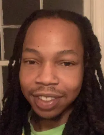 Smiling person with long braids indoors