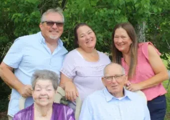 Multigenerational family portrait outdoors with greenery backdrop