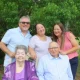 Multigenerational family portrait outdoors with greenery backdrop
