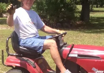 Man on red lawn mower holding object