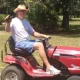 Man on red lawn mower holding object