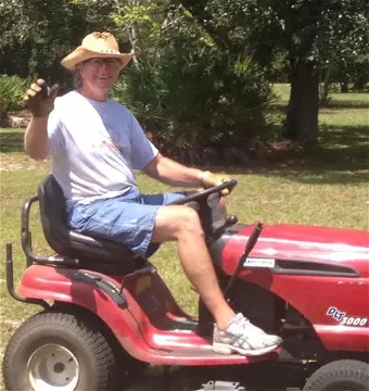 Man on red lawn mower holding object