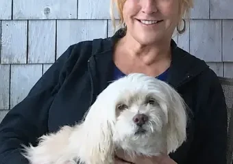 Woman holding small white dog outdoors