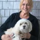 Woman holding small white dog outdoors