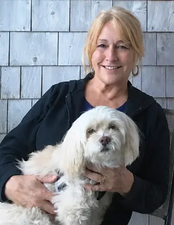 Woman holding small white dog outdoors