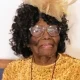 Elderly woman in yellow dress and decorative hat