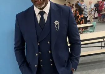 Man in navy suit leaning against wall