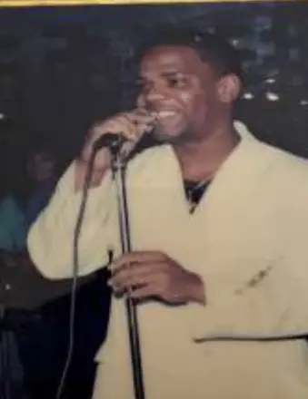 Man singing into microphone on stage