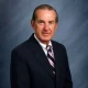Older man in suit against blue backdrop