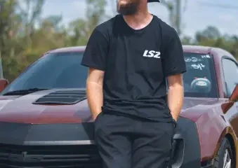 Bearded man in sunglasses leaning on red sports car